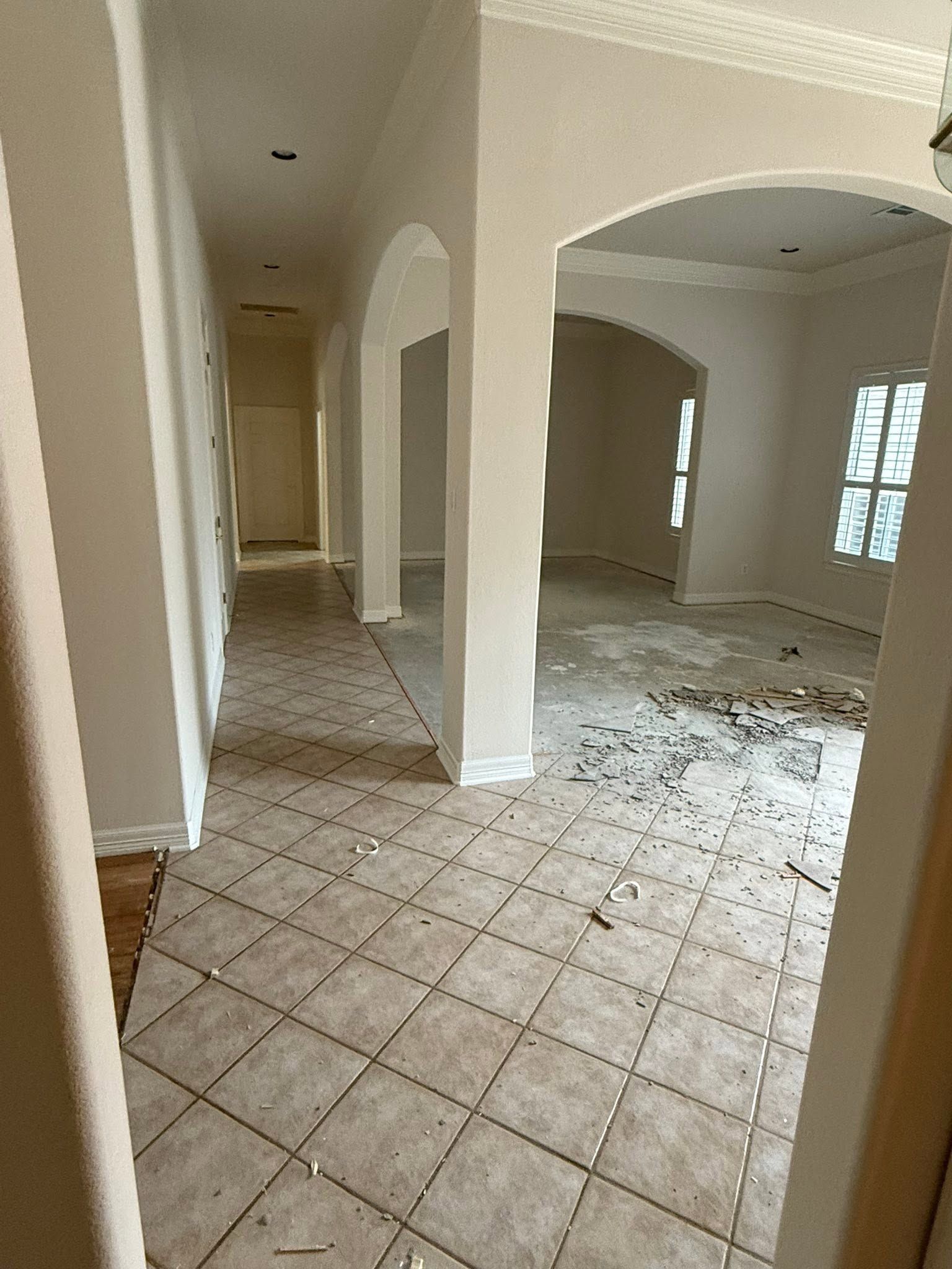 Empty hallway with tiled floor and arched openings in a partly damaged interior.