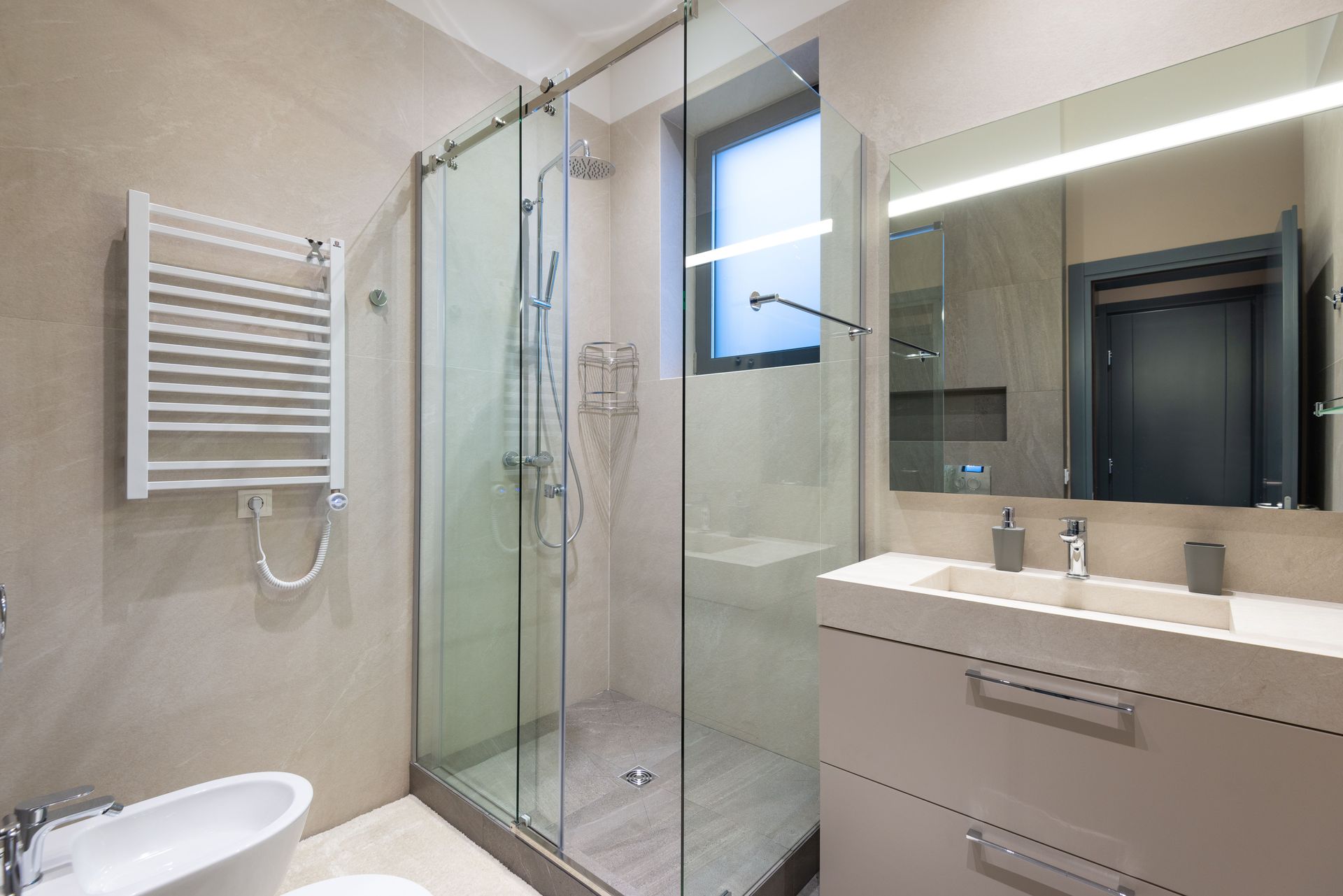 Modern bathroom with glass shower, towel rack, sink vanity, and large mirror.