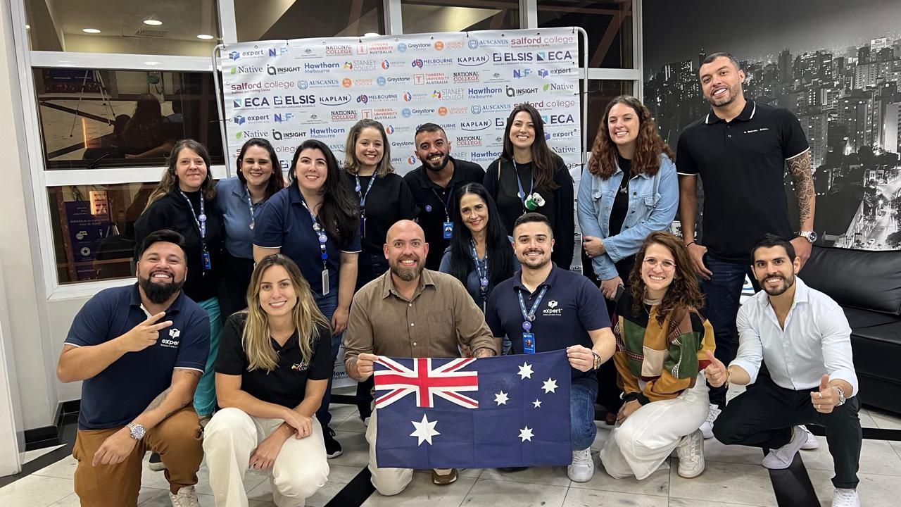 Um grupo de pessoas posa para uma foto enquanto segura uma bandeira australiana.