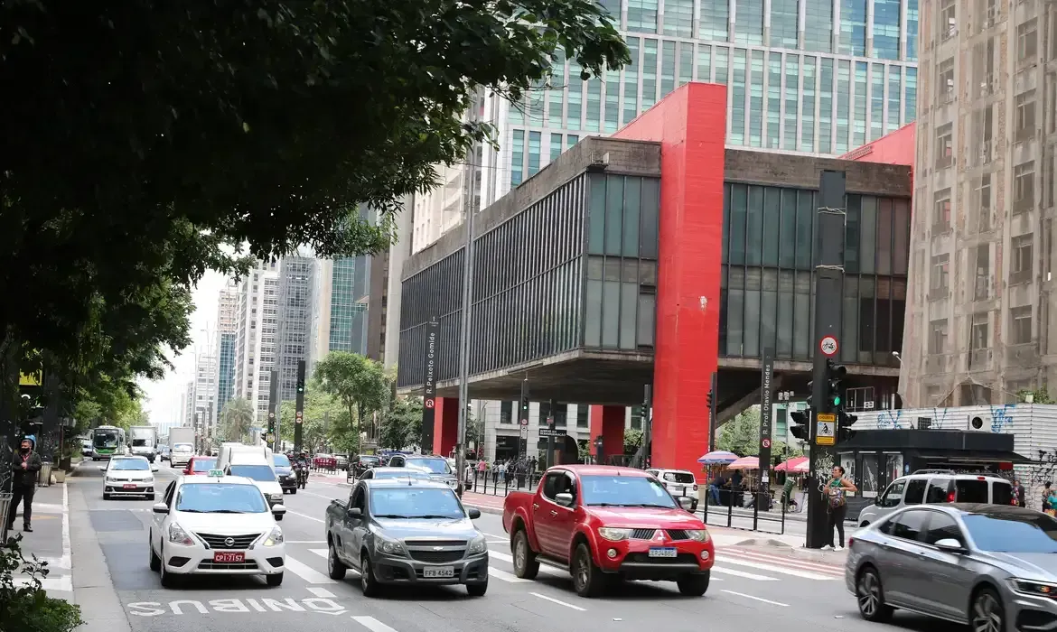 Uma rua movimentada da cidade com um prédio vermelho ao fundo