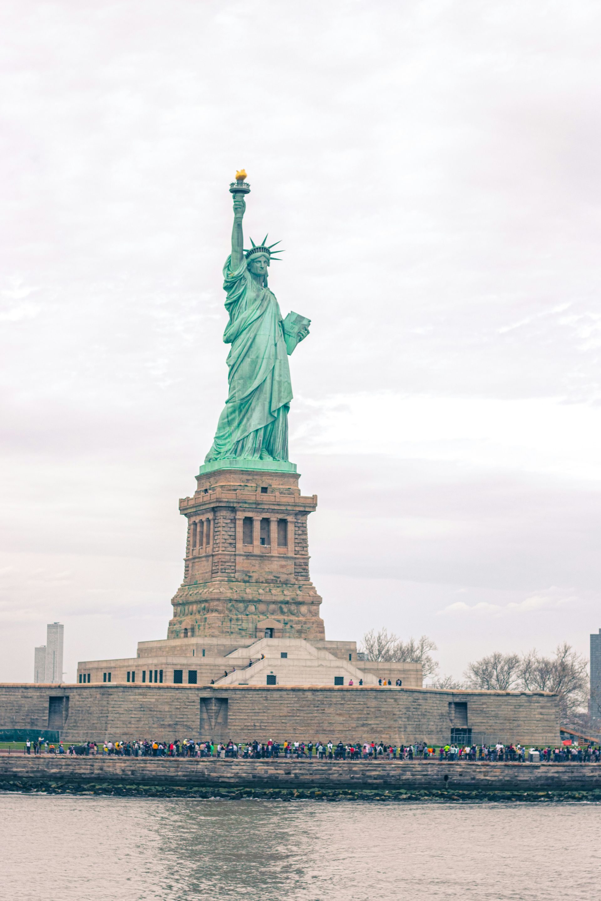 A estátua da liberdade é cercada por água na cidade de Nova York.