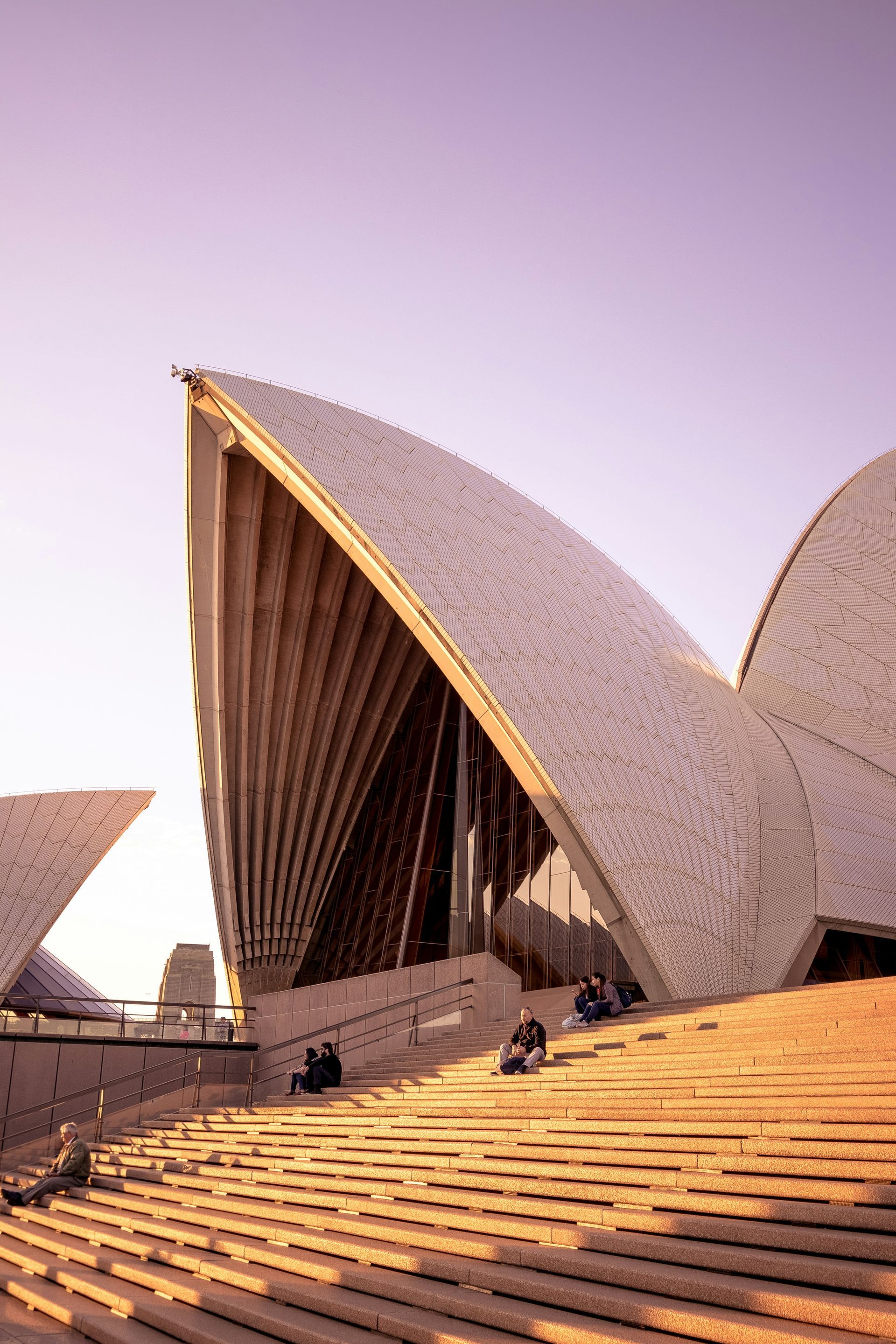 Um grupo de pessoas está sentado nos degraus da Ópera de Sydney.