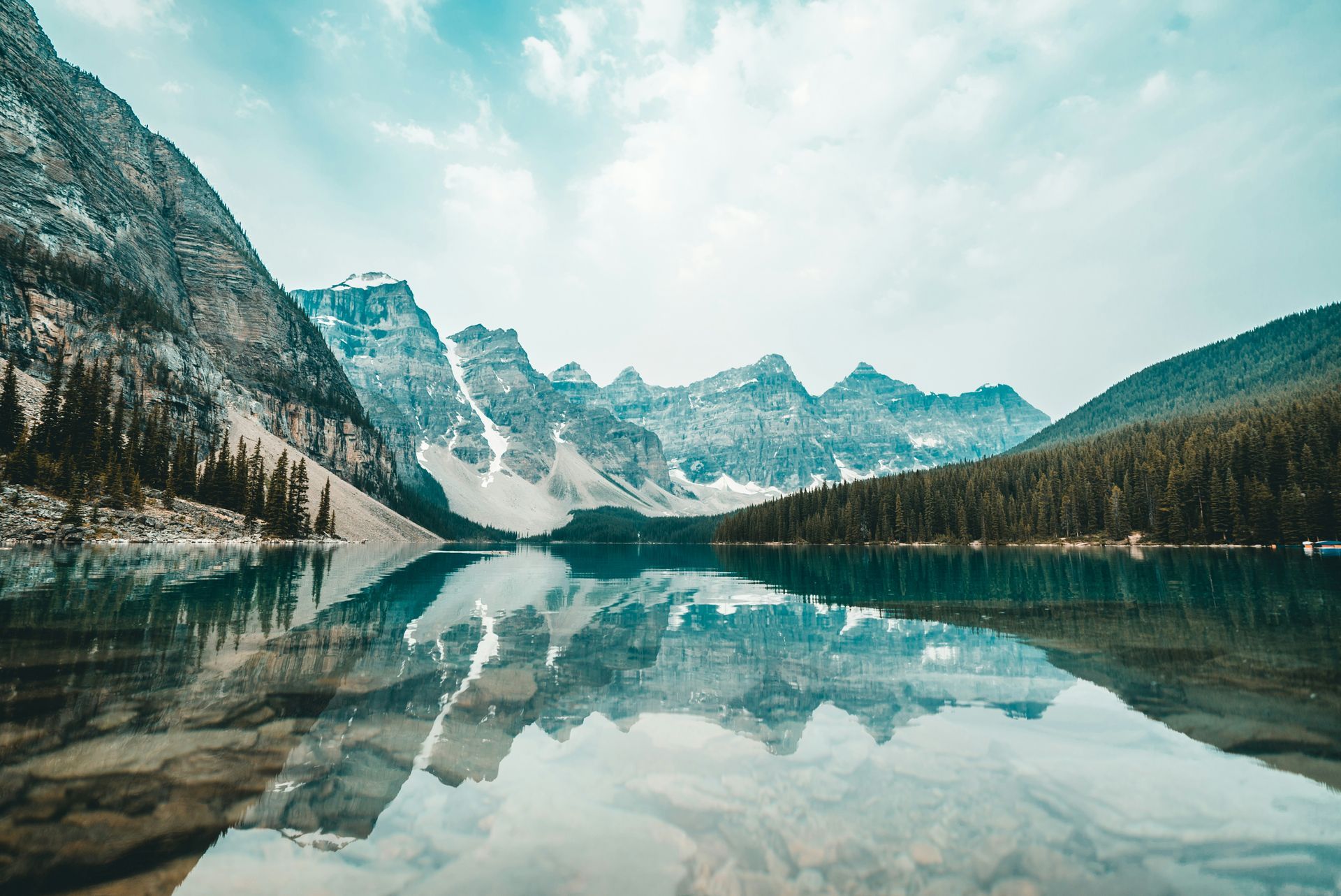 Um lago cercado por montanhas e árvores se reflete na água.