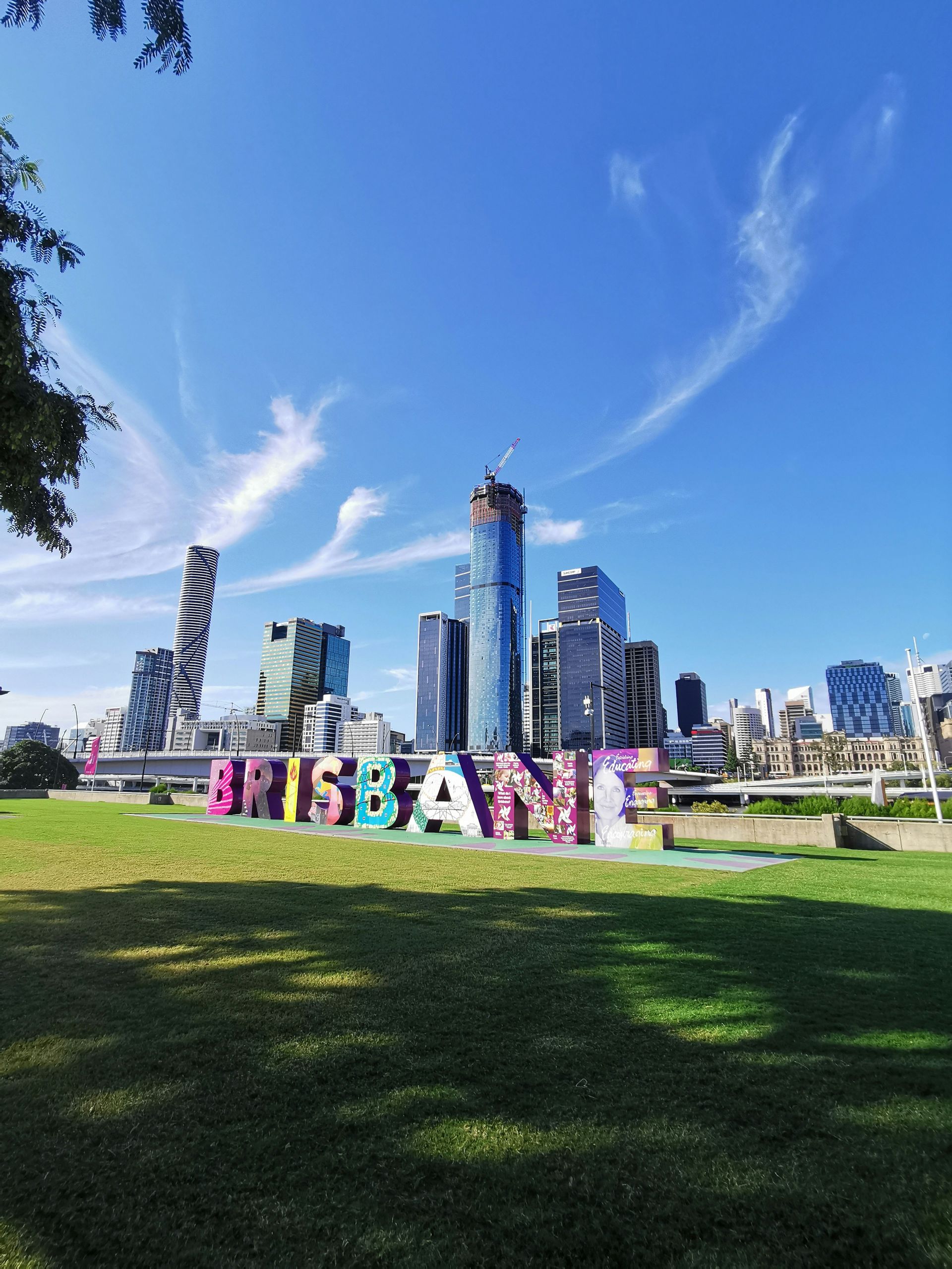 Uma placa que diz Brisbane em frente ao horizonte de uma cidade.