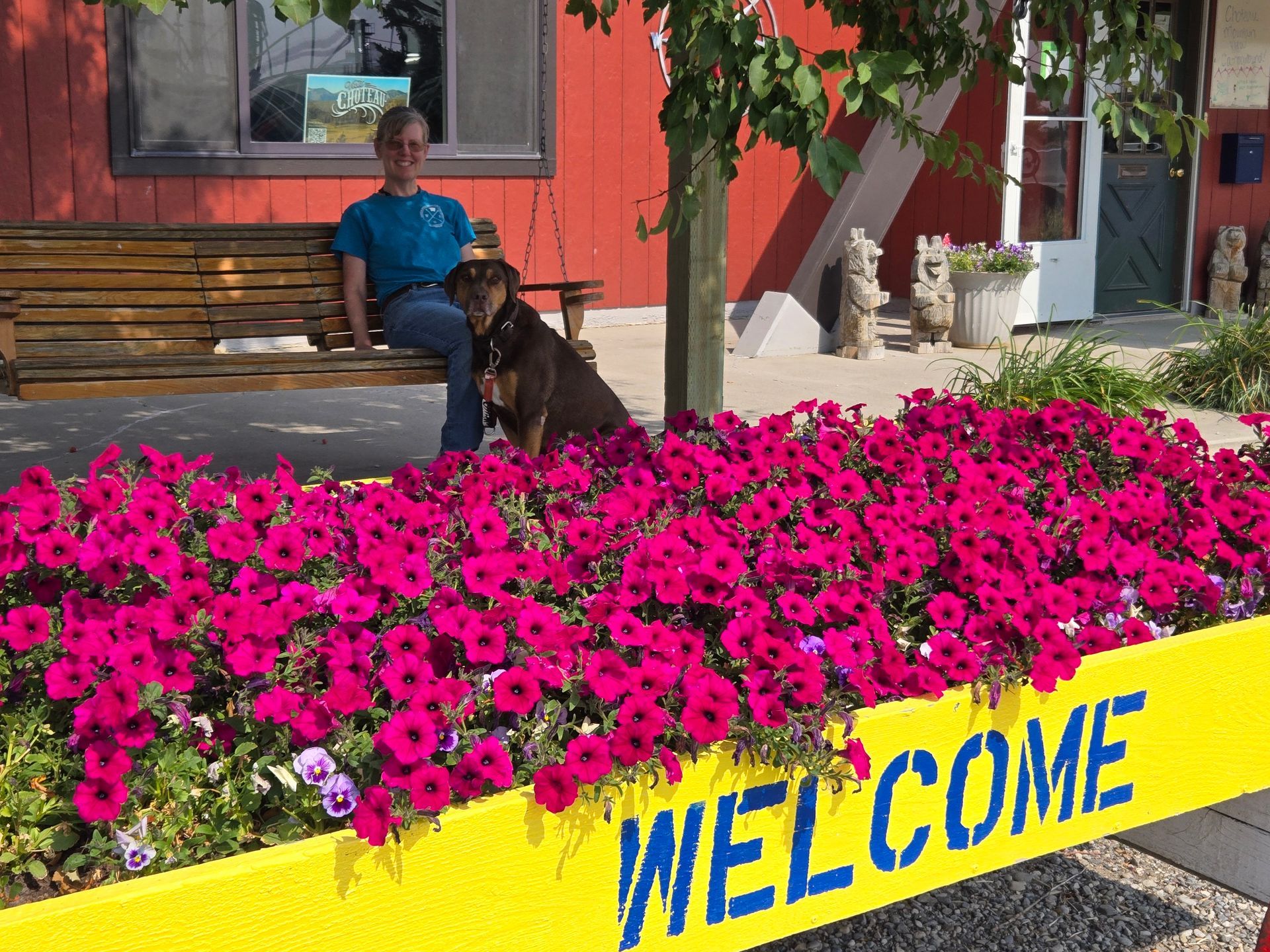 Person and dog on bench by pink flowers and 