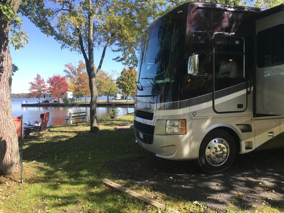 Motorhome parked by a lakeside campsite with trees and autumn leaves