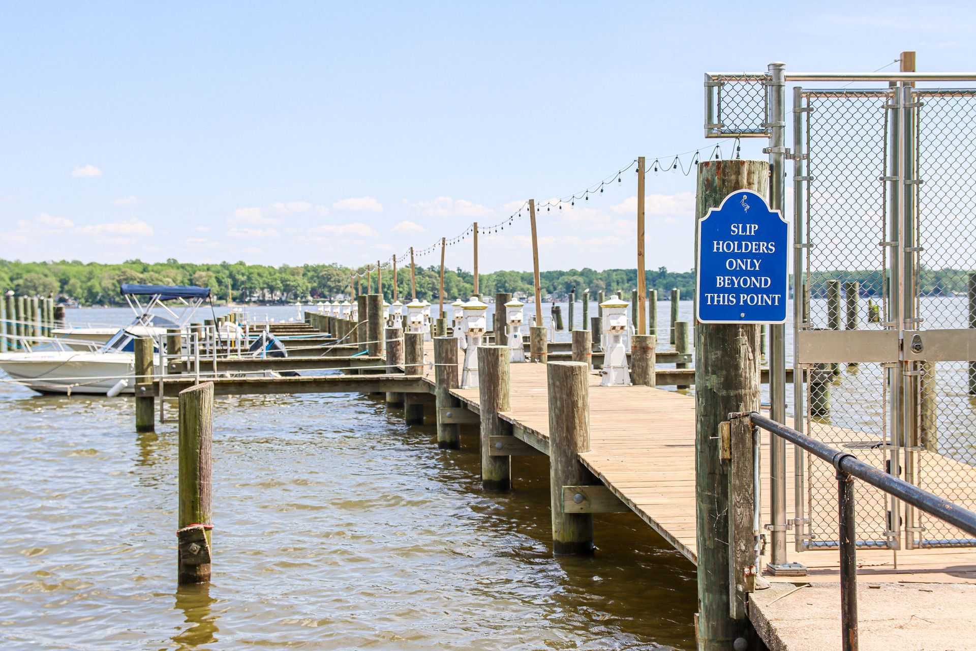 Wooden dock with boats on a calm waterfront, beside a blue no swimming sign.