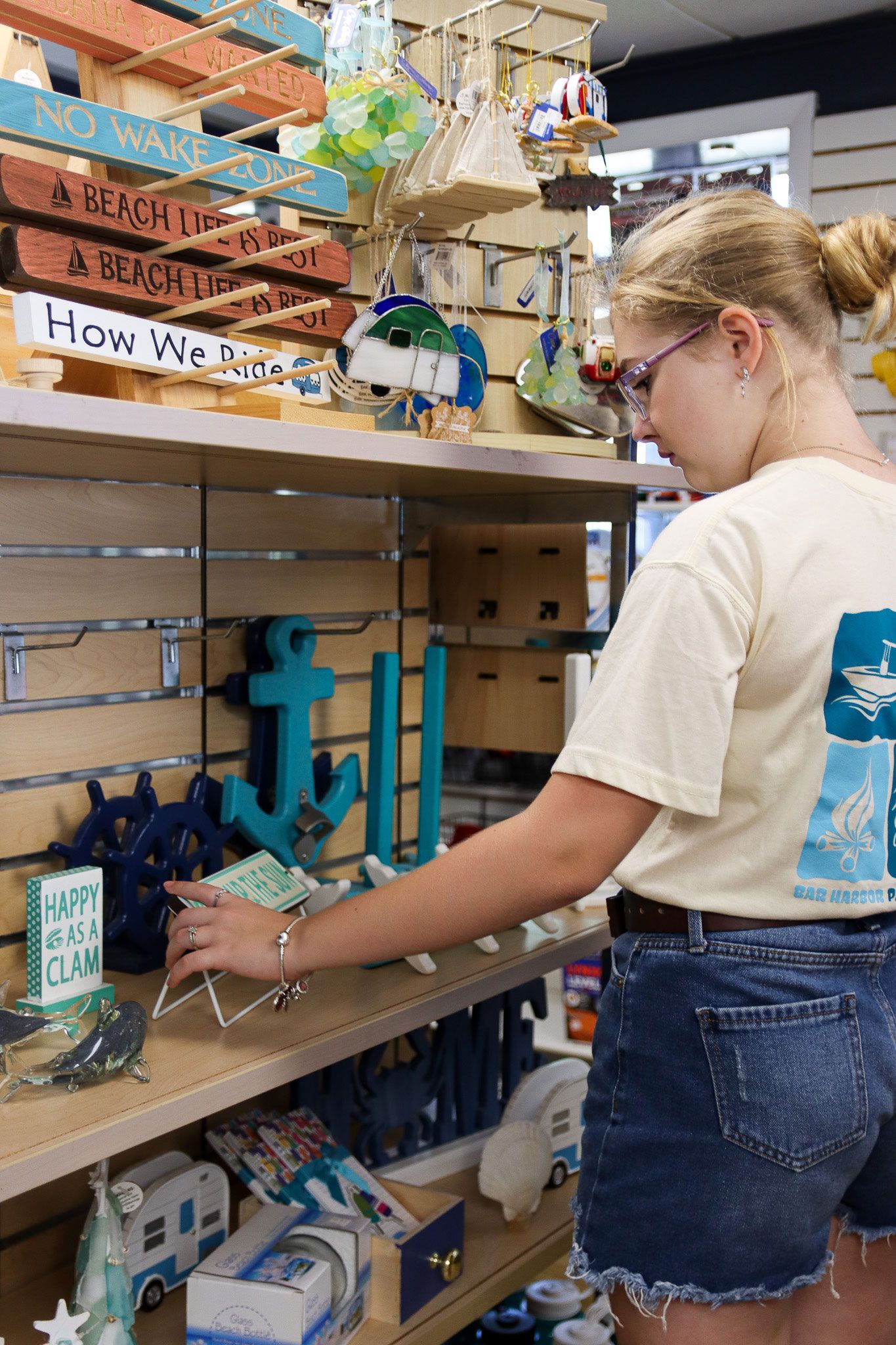 Person in a store aisle arranging items on a shelf, with craft supplies and signs nearby.
