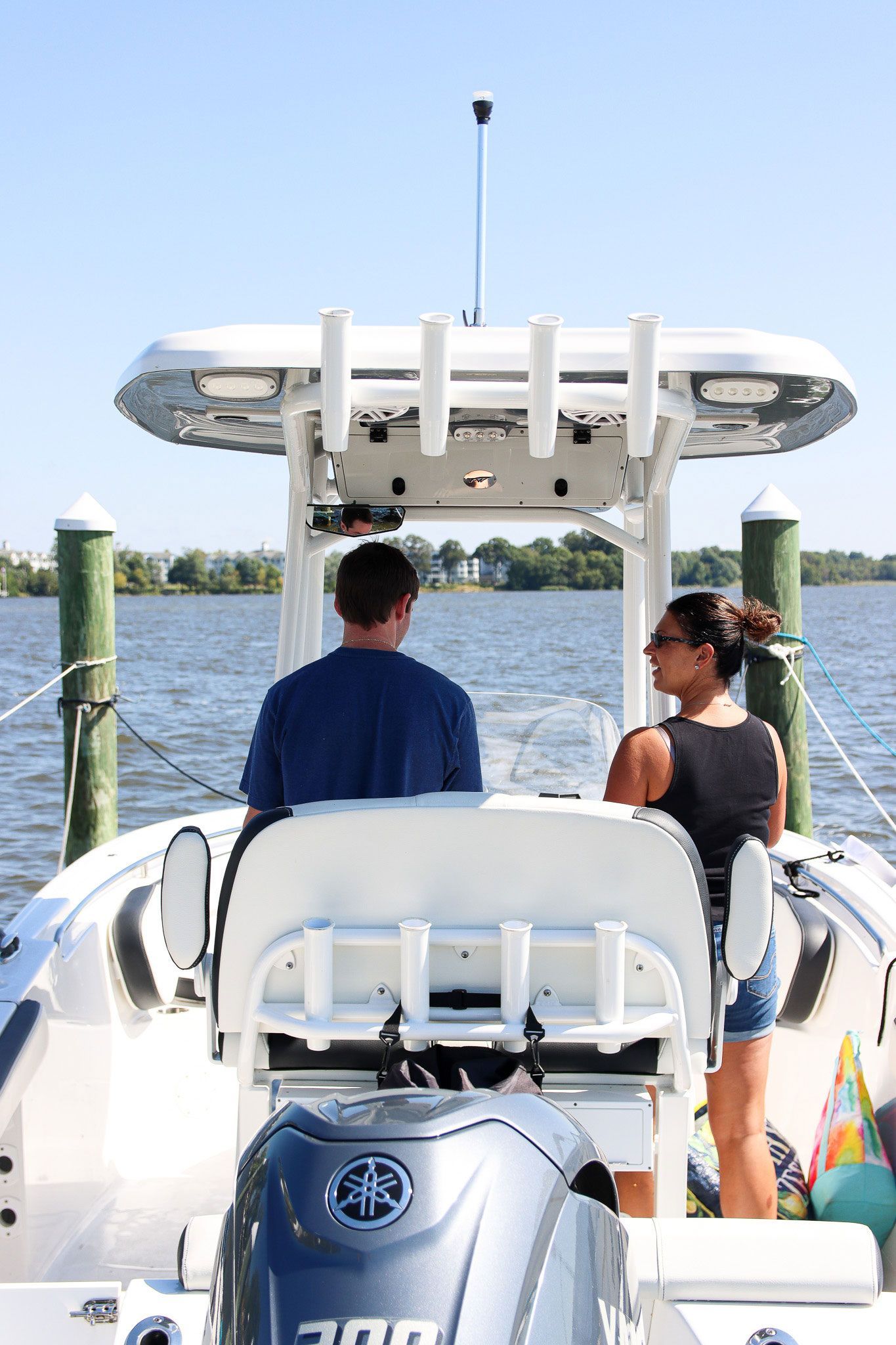 Two people on a white motorboat on calm water under a clear sky