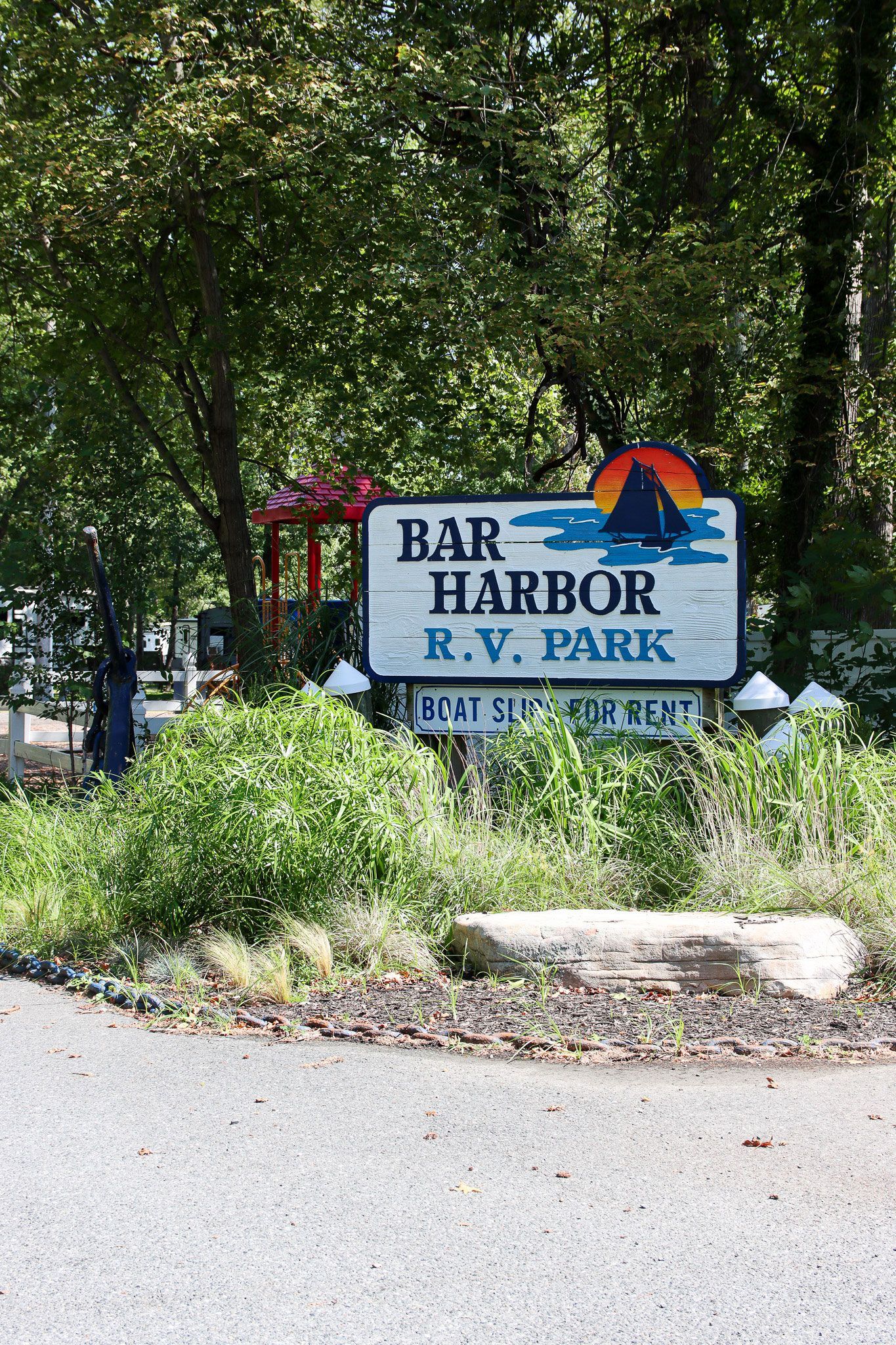 Bähr Harbor RV Park sign amid trees and shrubs by a gravel roadside