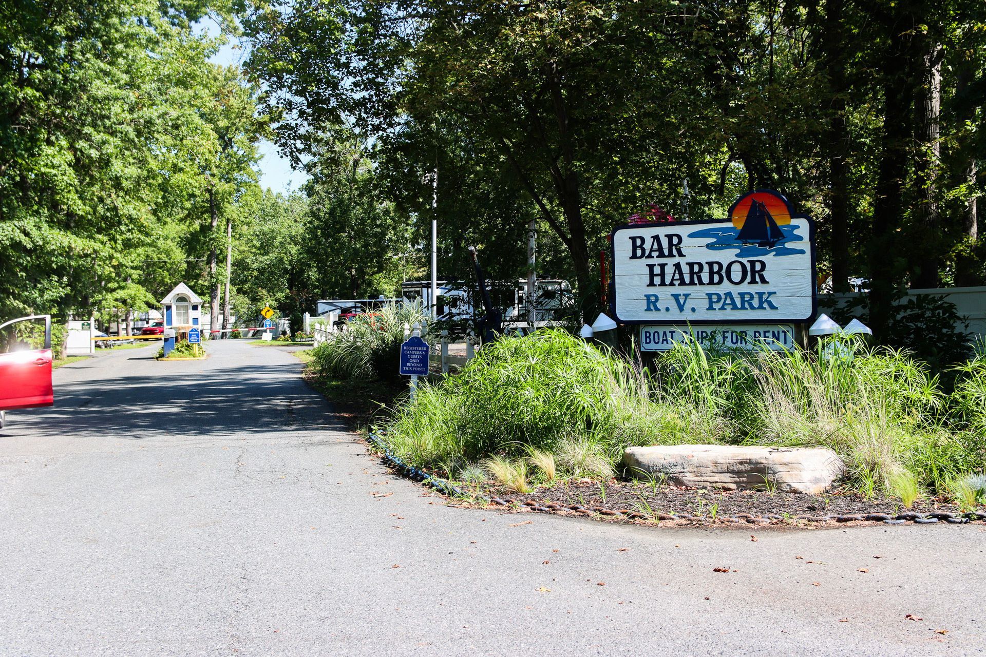 Entrance sign for Bar Harbor R.V. Park along a tree-lined gravel road