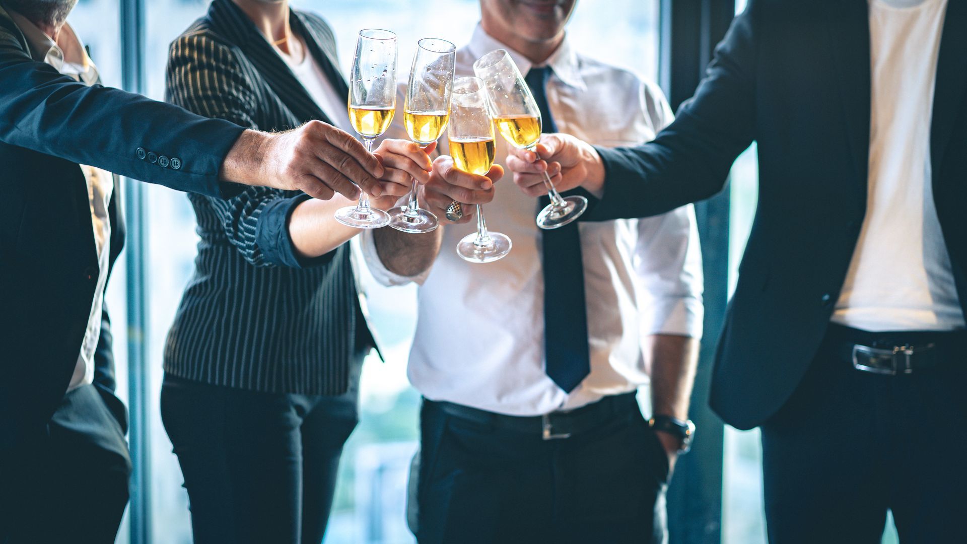 Business people in suits toasting drinks in an office setting