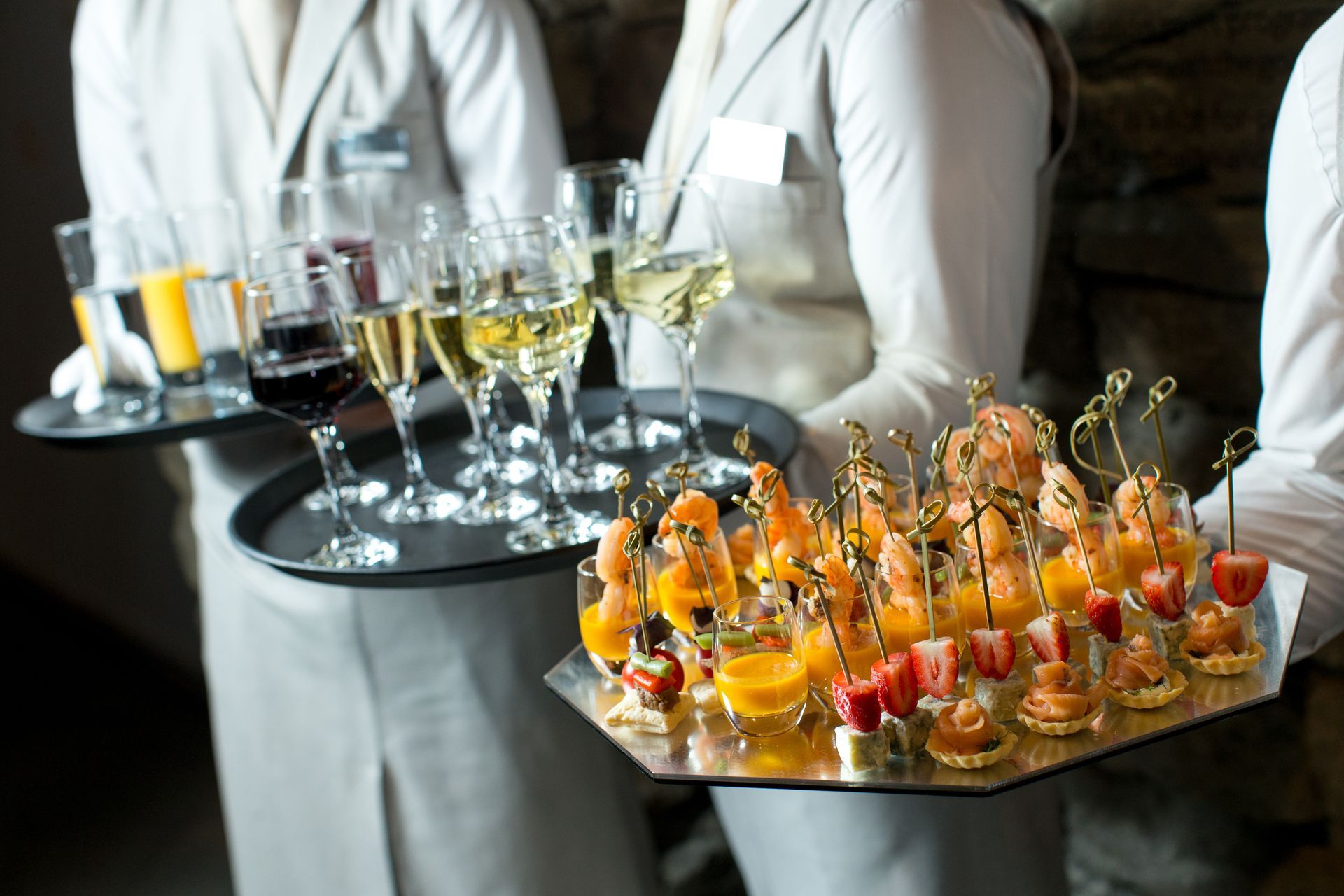 Waiter carrying trays of colorful champagne and dessert hors d’oeuvres at a catered event Waiter carrying trays of colorful champagne and dessert hors d’oeuvres at a catered event