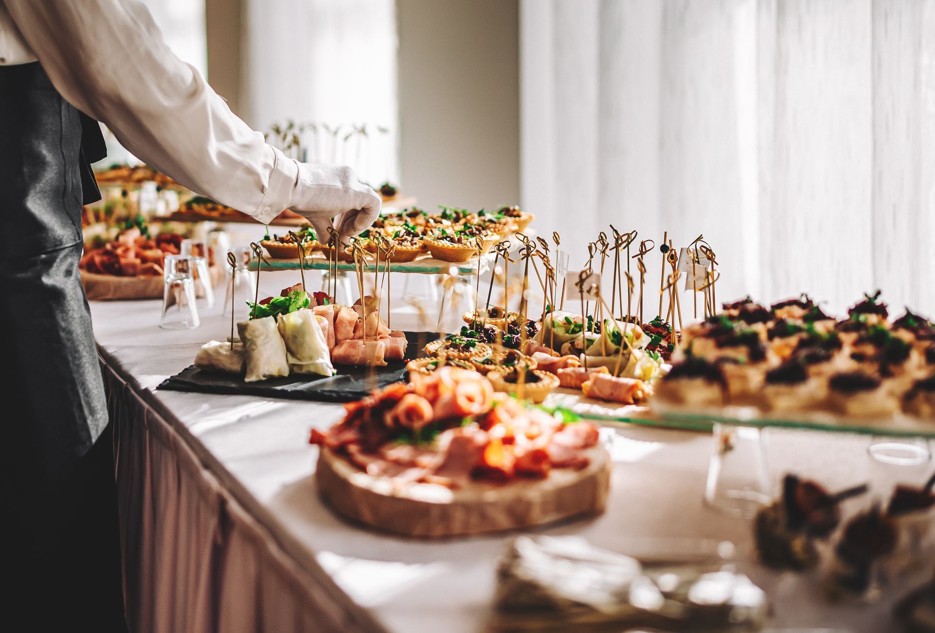 Buffet table with assorted appetizers and desserts being arranged at a catered event