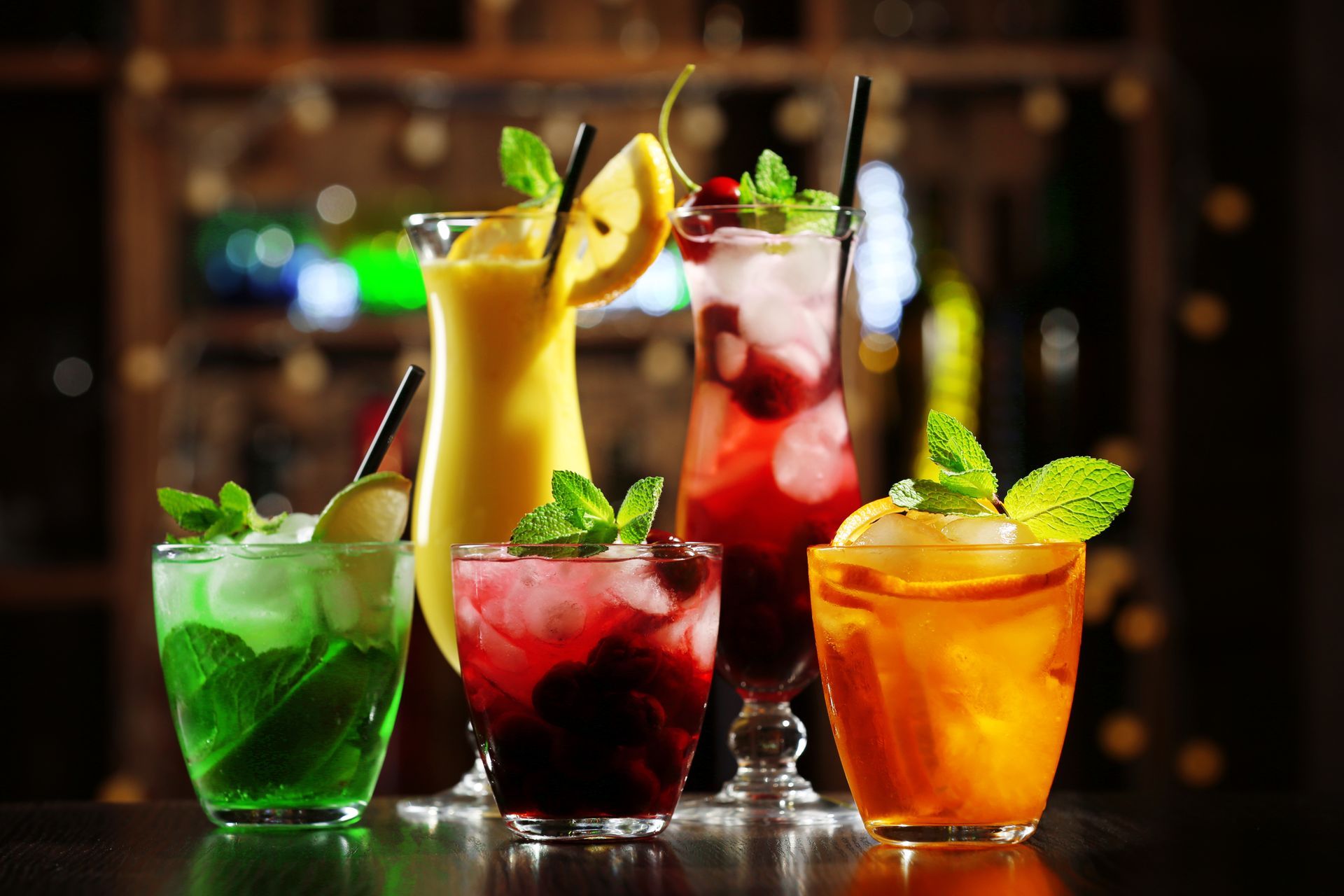 Assorted colorful cocktails with fruit garnish on a bar counter