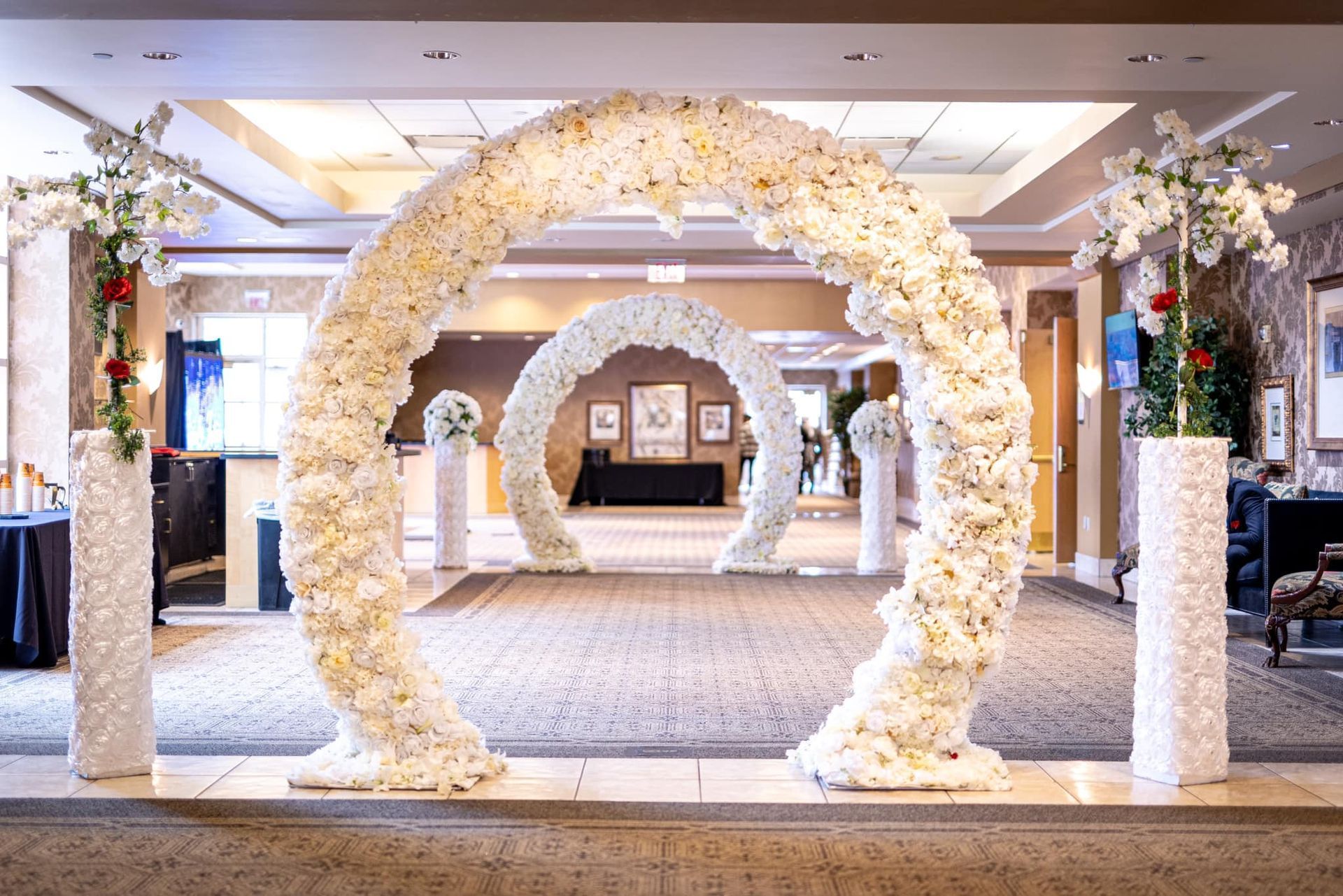 Floral archway decorated with white flowers in a bright indoor event venue