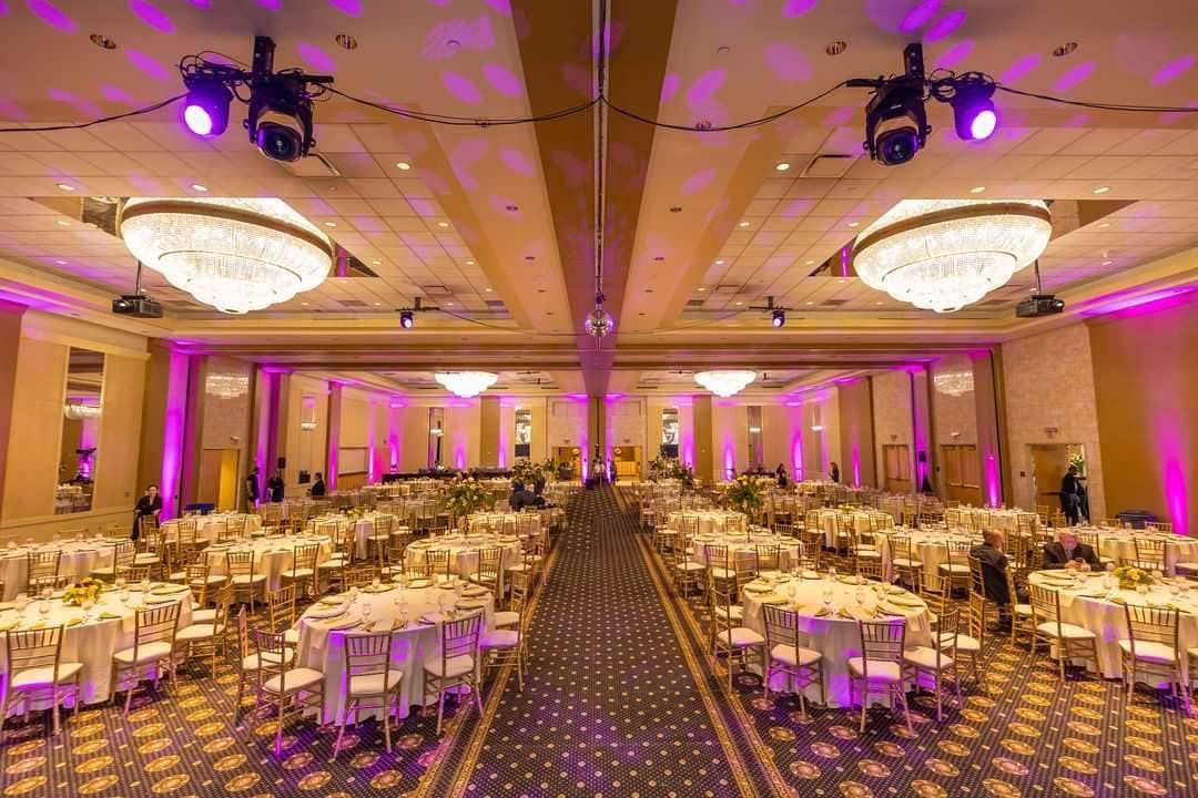Elegant banquet hall with purple lighting, round tables, and patterned carpet arranged for an event