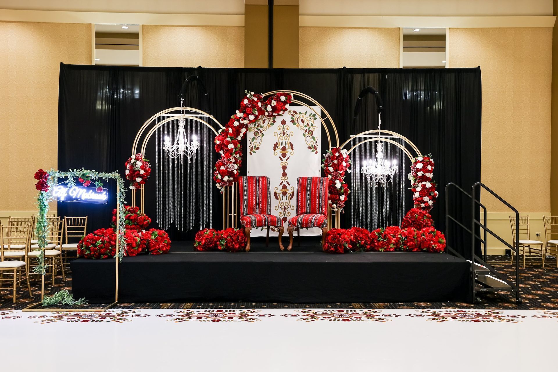 Festive holiday stage with red-and-white decorations, wreaths, arches, and a throne chair on a black platform