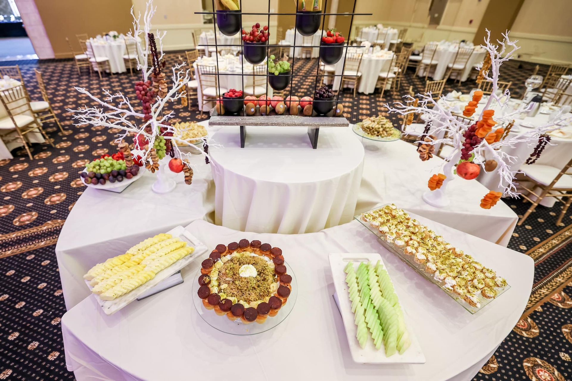 Elegant dessert buffet with assorted pastries arranged on white round tables and tiered stands
