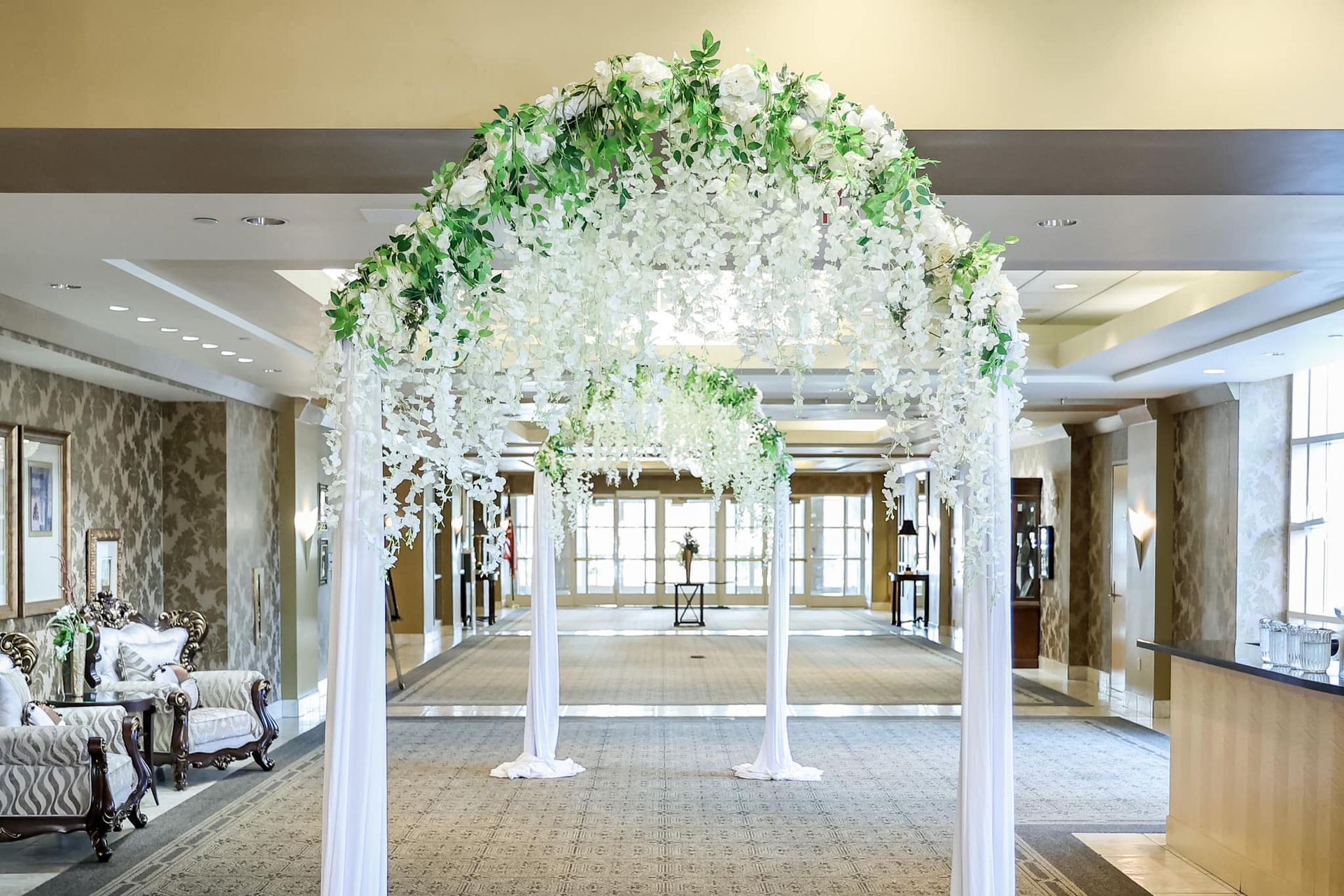 White floral archway in a bright hotel lobby with carpeted hallway beyond
