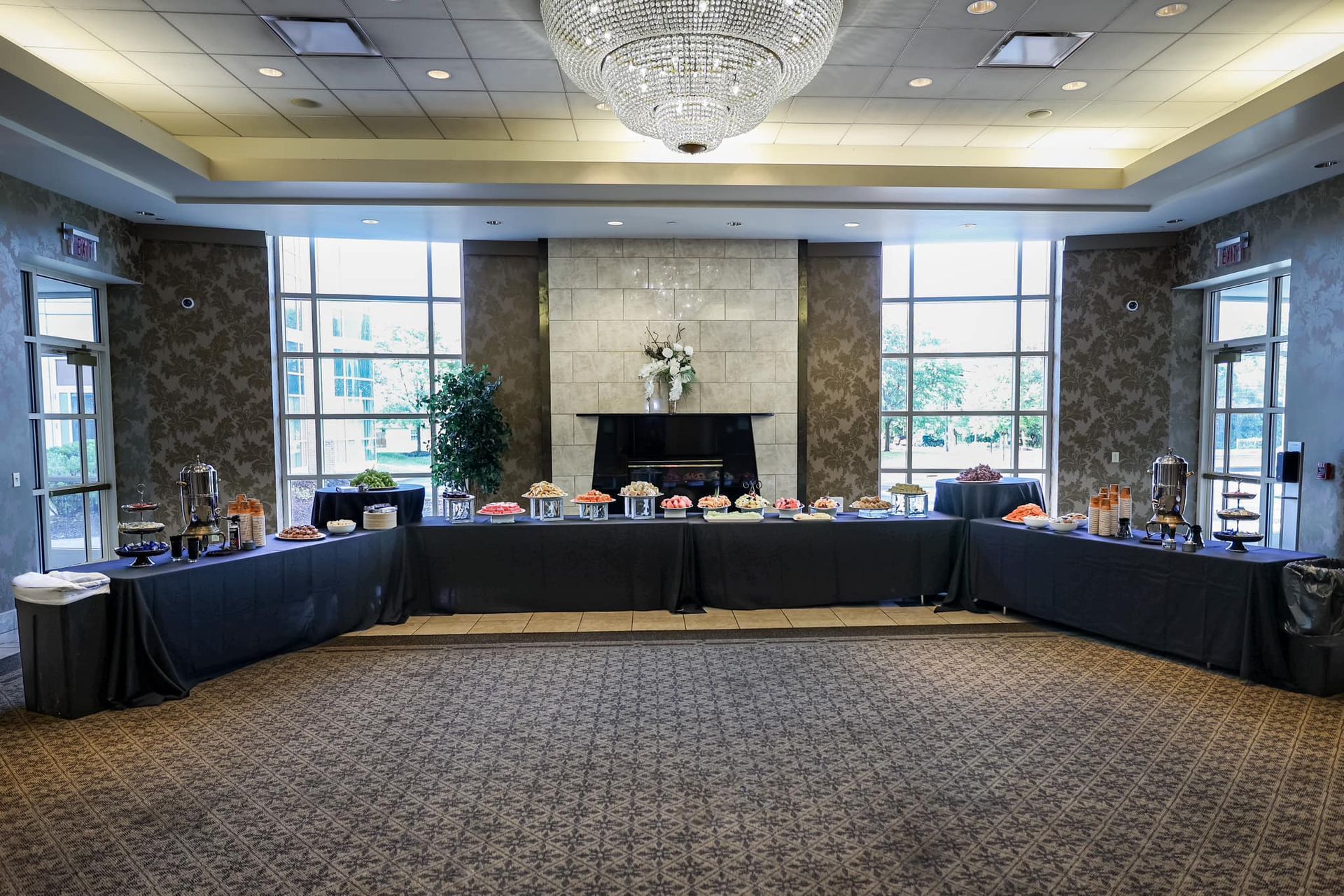 Formal banquet room with U-shaped tables, chairs, floral centerpieces, and a chandelier overhead