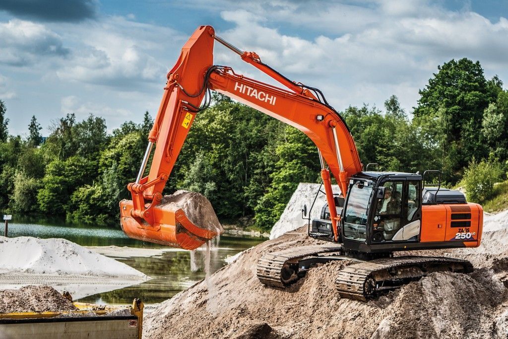 A large orange excavator is sitting on top of a pile of dirt.
