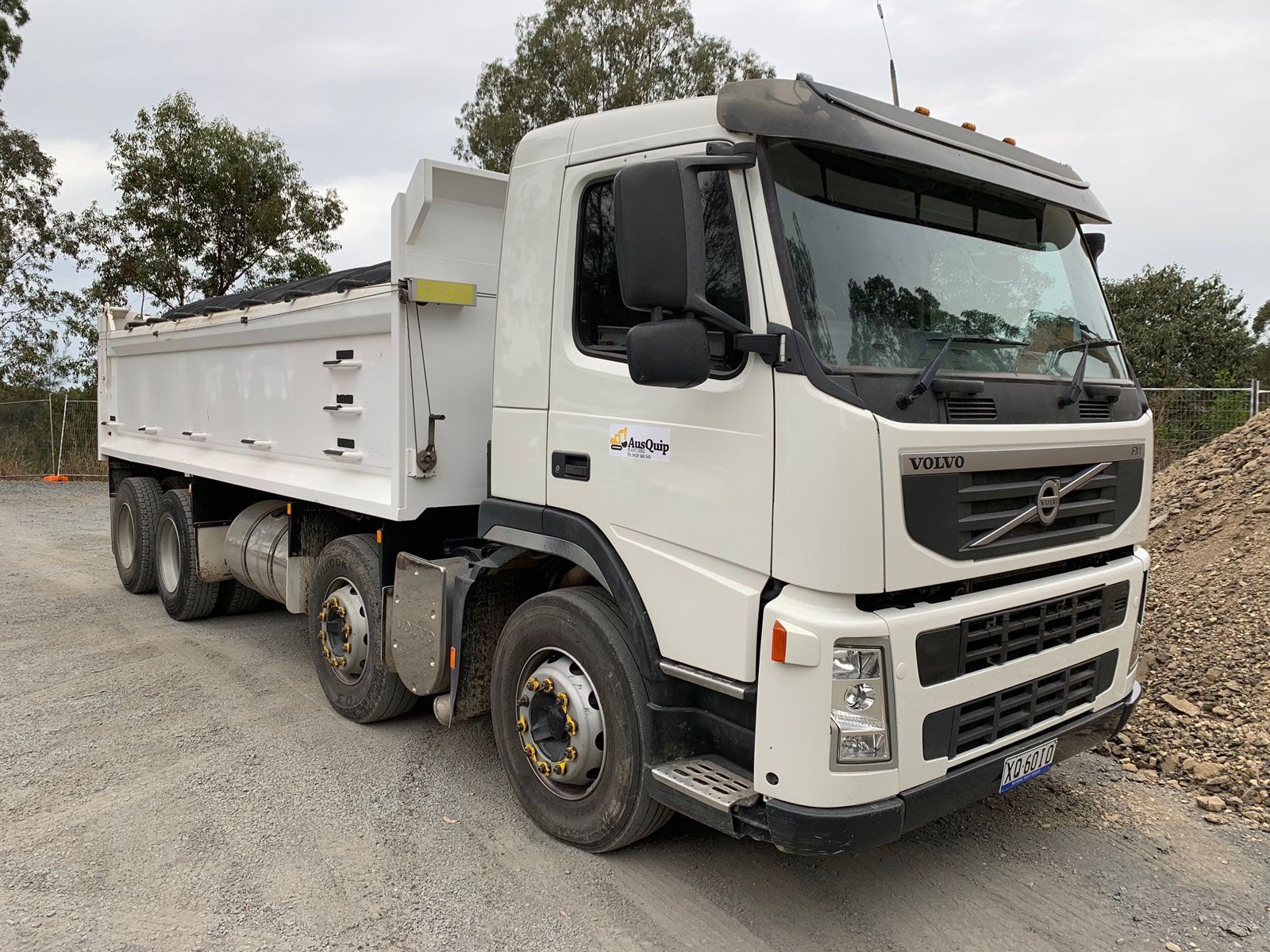 A dump truck parked on a gravel surface.