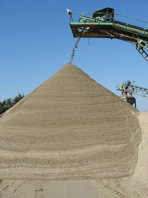 A large pile of dirt is being loaded onto a conveyor belt