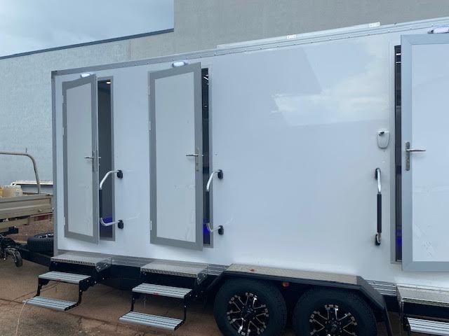 A White Trailer With Three Doors and Steps is Parked in Front of a Building — Ecotreat Solutions NT in Winnellie, NT