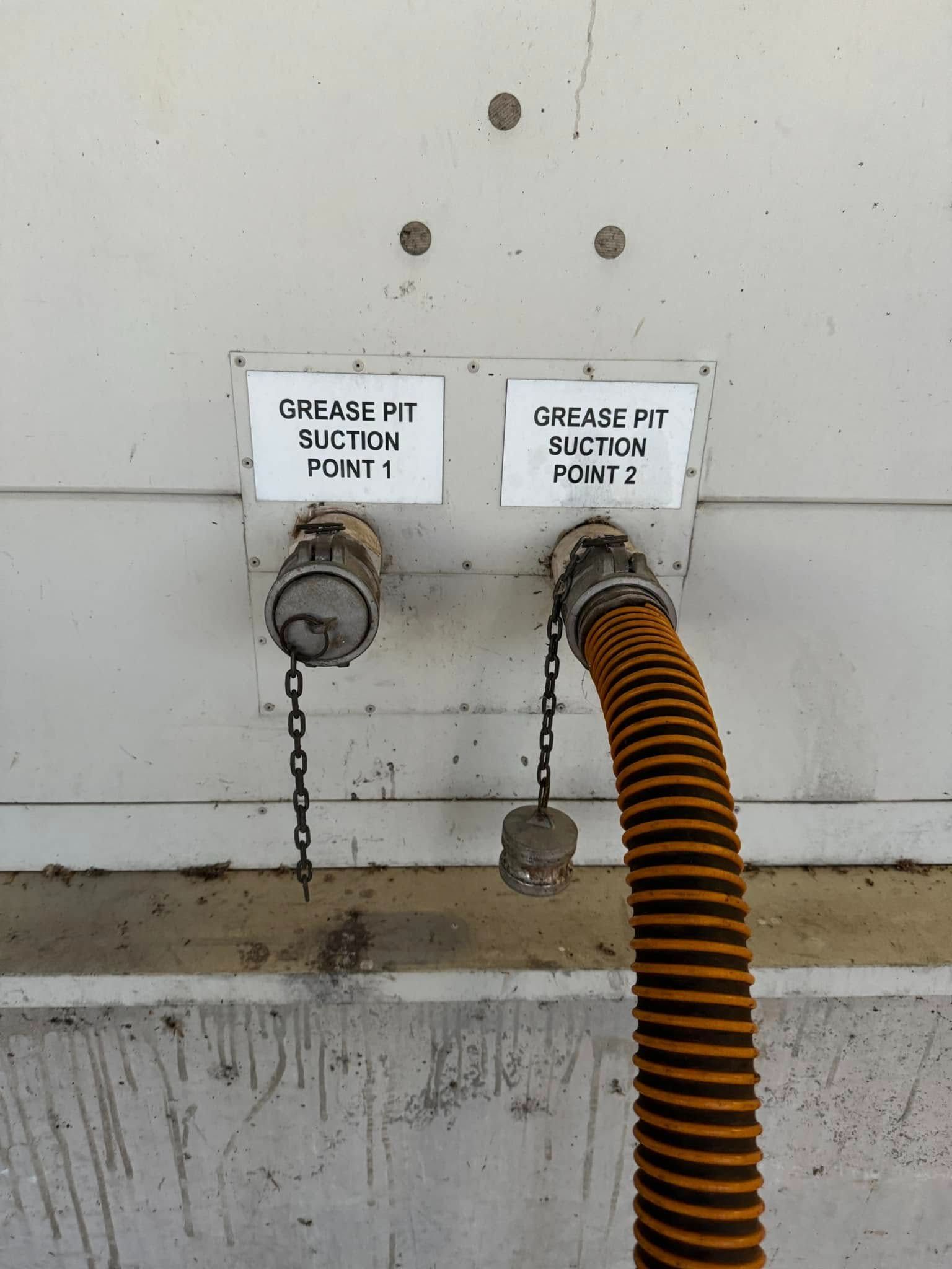 A Hose is Attached to a Wall With Two Signs That Say Grease Pit — Ecotreat Solutions NT in Winnellie, NT