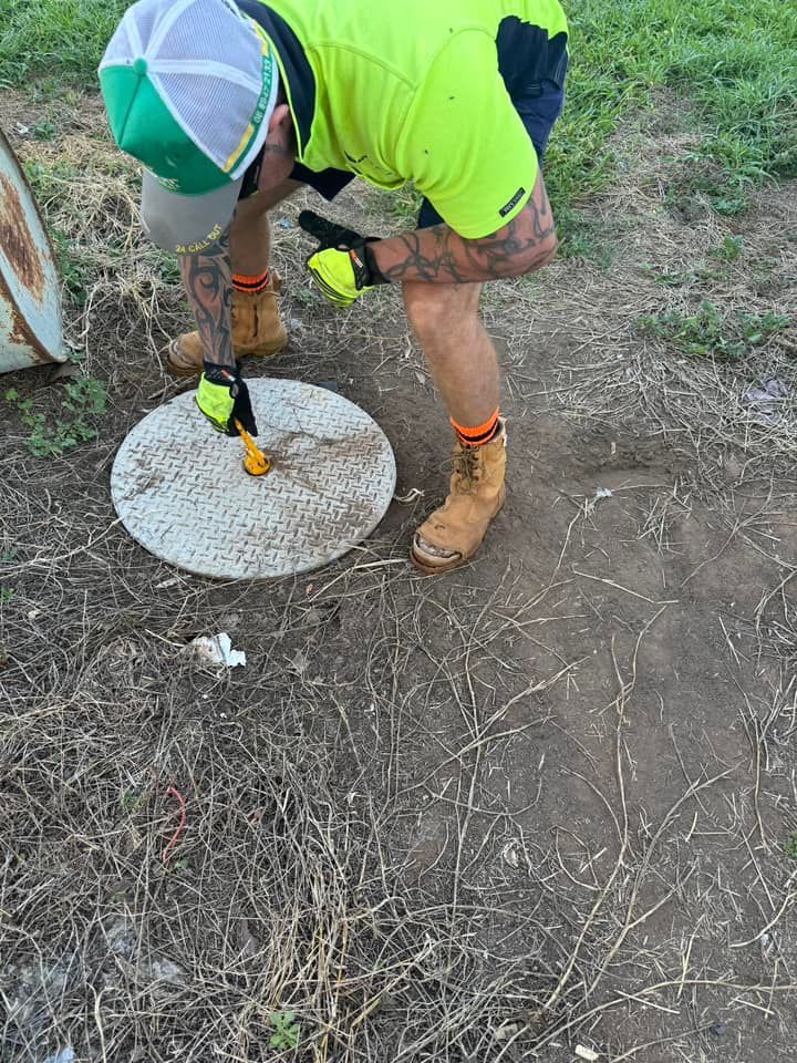 A Man is Measuring a Manhole Cover With a Tape Measure — Ecotreat Solutions NT in Darwin City, NT