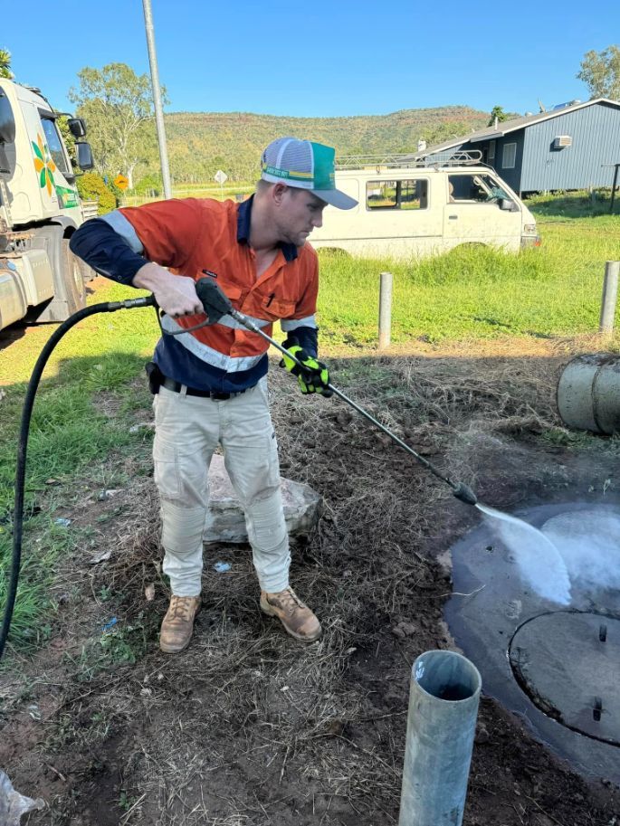 A Man is Cleaning a Manhole Cover With a High Pressure Washer — Ecotreat Solutions NT in Winnellie, NT