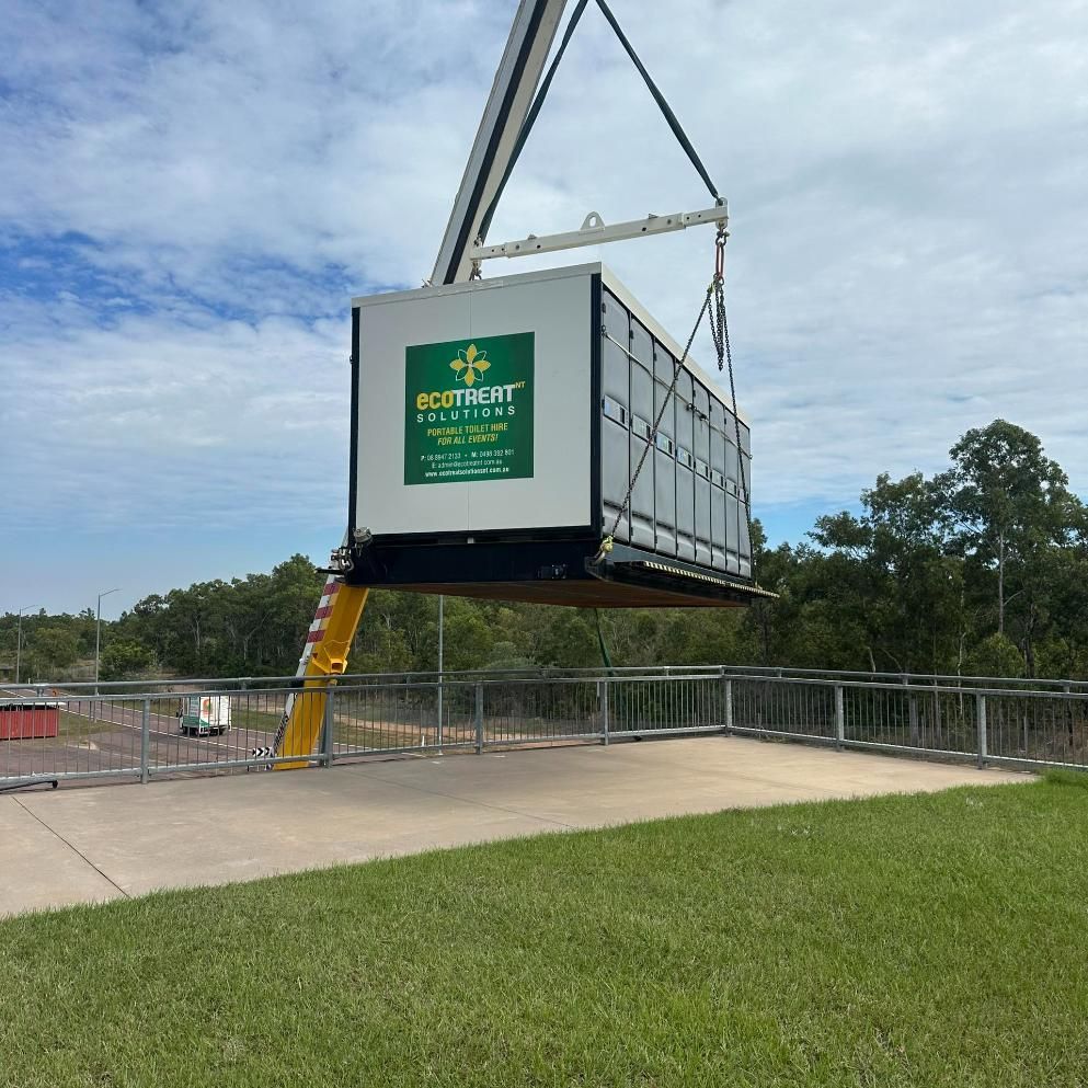 A White Container With a Green Logo is Suspended by a Crane Over a Walkway — Ecotreat Solutions NT In Winnellie, NT