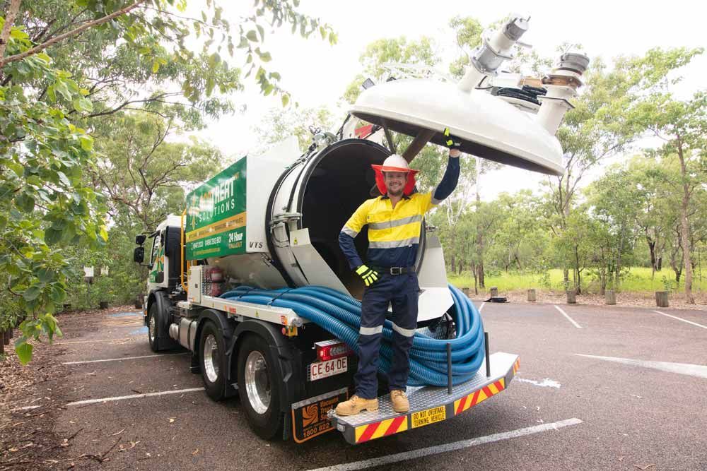 A Man is Standing Next to a Vacuum Truck in a Parking Lot — Ecotreat Solutions NT in Humpty Doo, NT