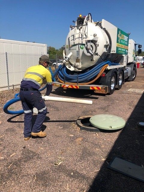 Man is Standing in Front of a Vacuum Truck Holding It — Ecotreat Solutions NT in Winnellie, NT