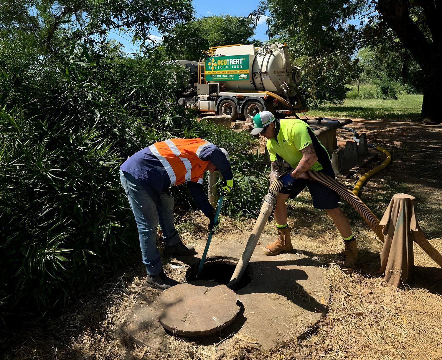 Two People Cleaning A Septic Tank Using Vacuum Hose