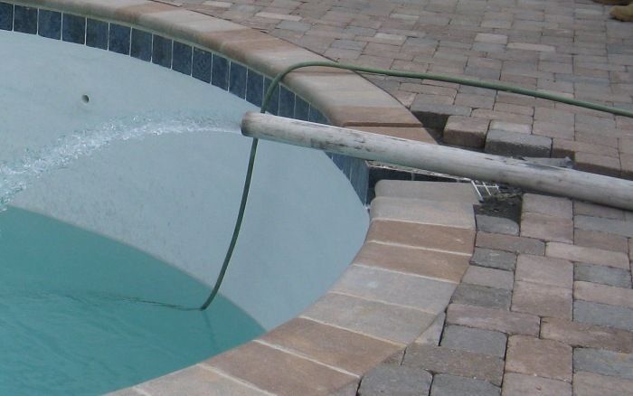 Swimming pool corner with a metal handrail and tiled deck beside the water