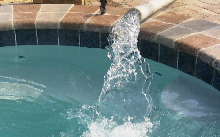 Water bubbling up in a small tiled pool, splashing into blue-green water.