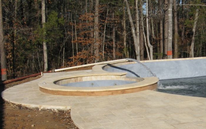 Circular concrete skate park bowl surrounded by trees and a wooden deck