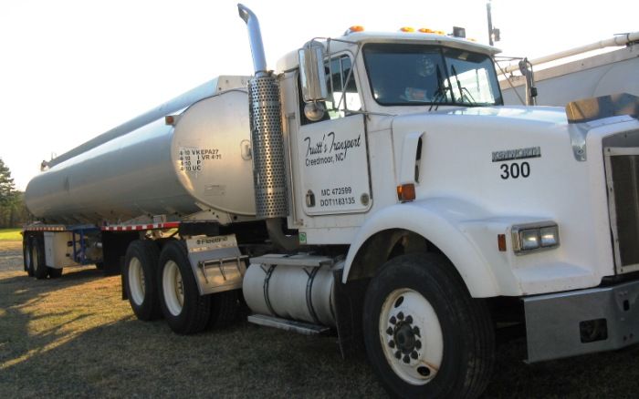 White tanker truck parked outdoors in daylight, side view with company logo on the door.