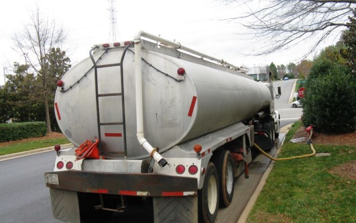 Silver tanker trailer parked on a roadside, with a ladder on the rear and red reflective markings.