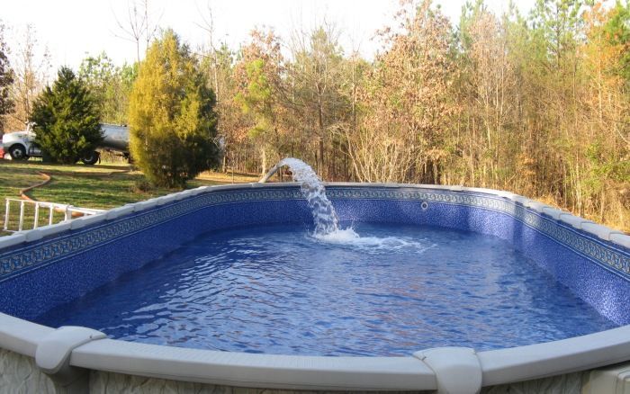 Backyard above-ground pool with blue water and a small fountain喷射
