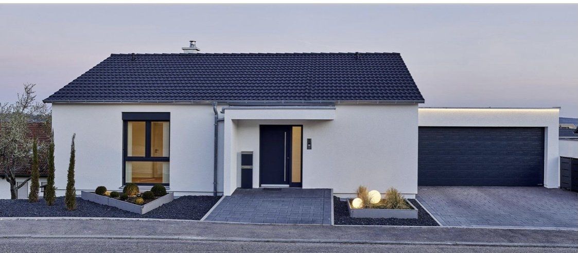 A white house with a black roof and a garage