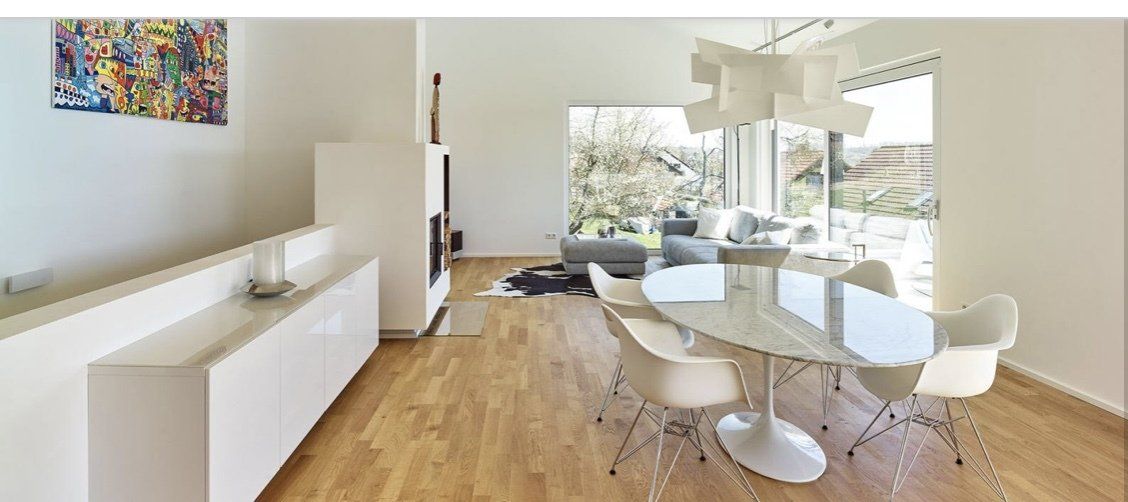 A living room with a table and chairs and a painting on the wall.