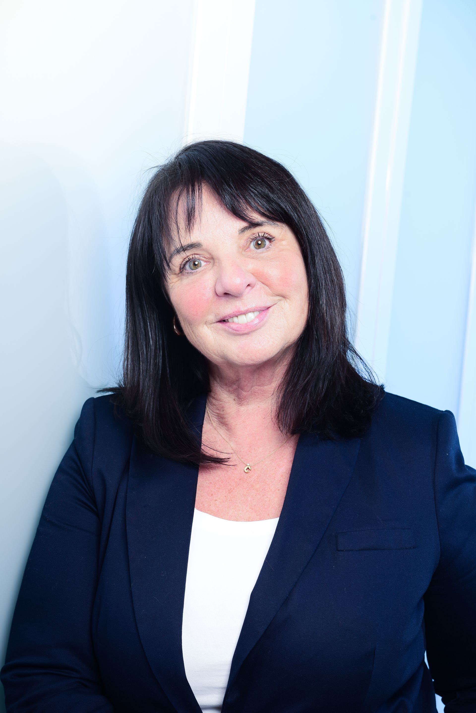 A woman in a blue jacket and white shirt is smiling for the camera.