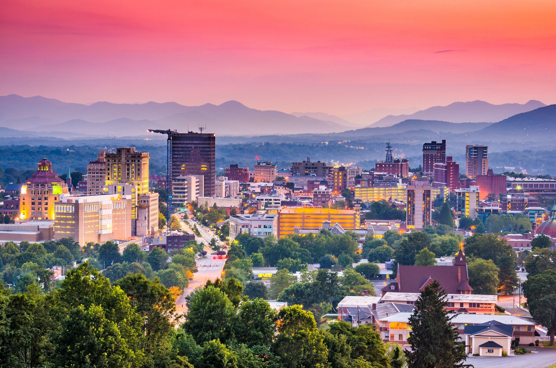 A city skyline at sunset with a pink sky, densely packed buildings, and hazy mountains in the distant background. A city skyline at sunset with a pink sky, densely packed buildings, and hazy mountains in the distant background.