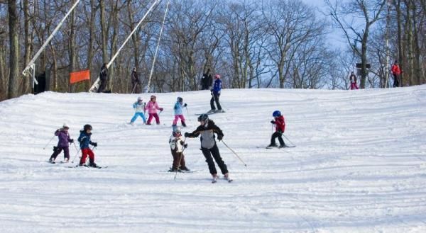 Skiers and snowboarders descend a snowy slope on a clear winter day.