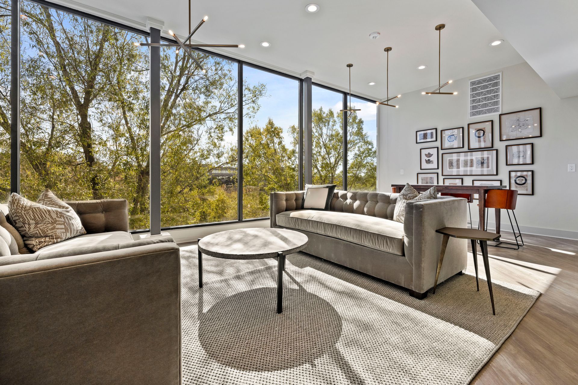 A living room with a couch , chairs , coffee table and large windows.