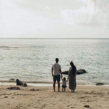 A family standing on a beach looking at the ocean