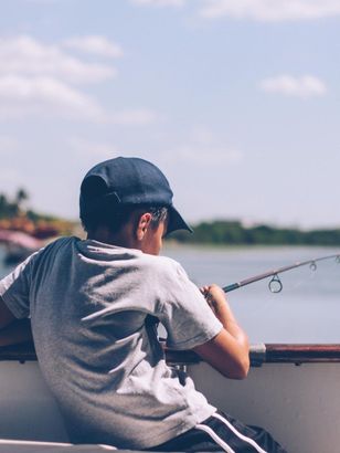 A young boy is sitting in a boat holding a fishing rod.